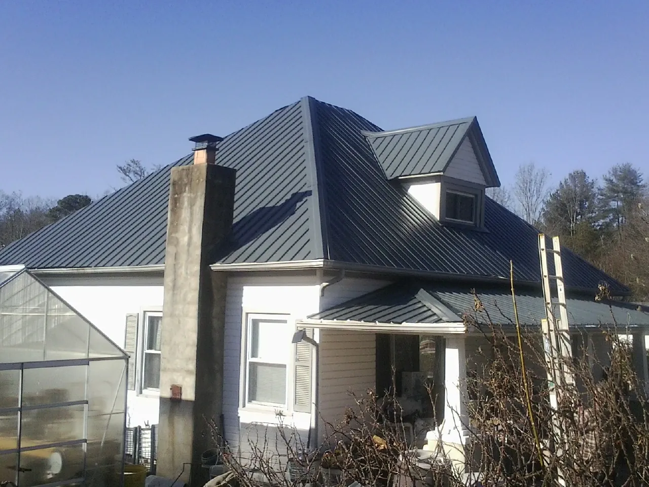 Dark blue standing seam metal roof on a white farmhouse with dormer — Slate & Tile Roof Repair by Roofing Brothers in Richardsville