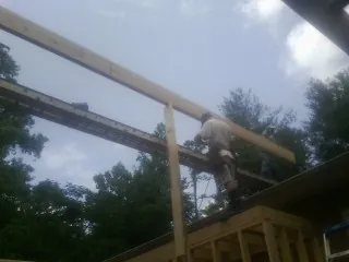 Carpenter setting a ridge beam over a new addition frame — Ice Dam Removal by Roofing Brothers in Richardsville