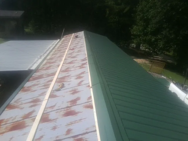 Old rusted panels beside newly installed green metal roofing — Wind Damage Roof Repair by Roofing Brothers in Richardsville