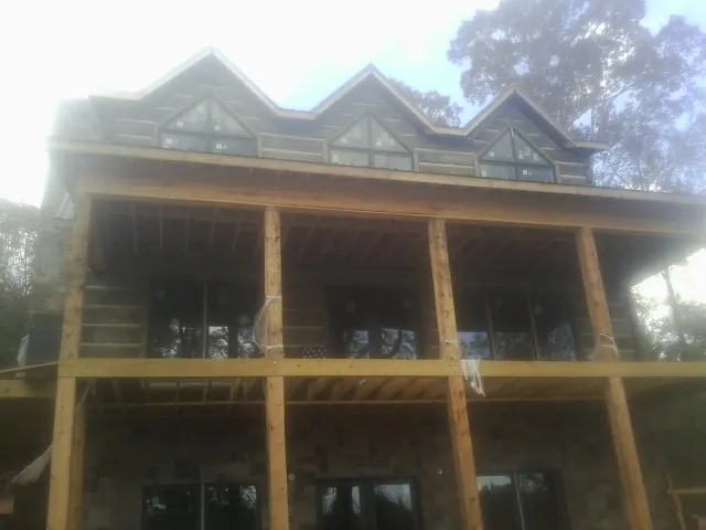 Dormers and porch framing on a large log home under construction — Roof Coating work by our crew in Richardsville