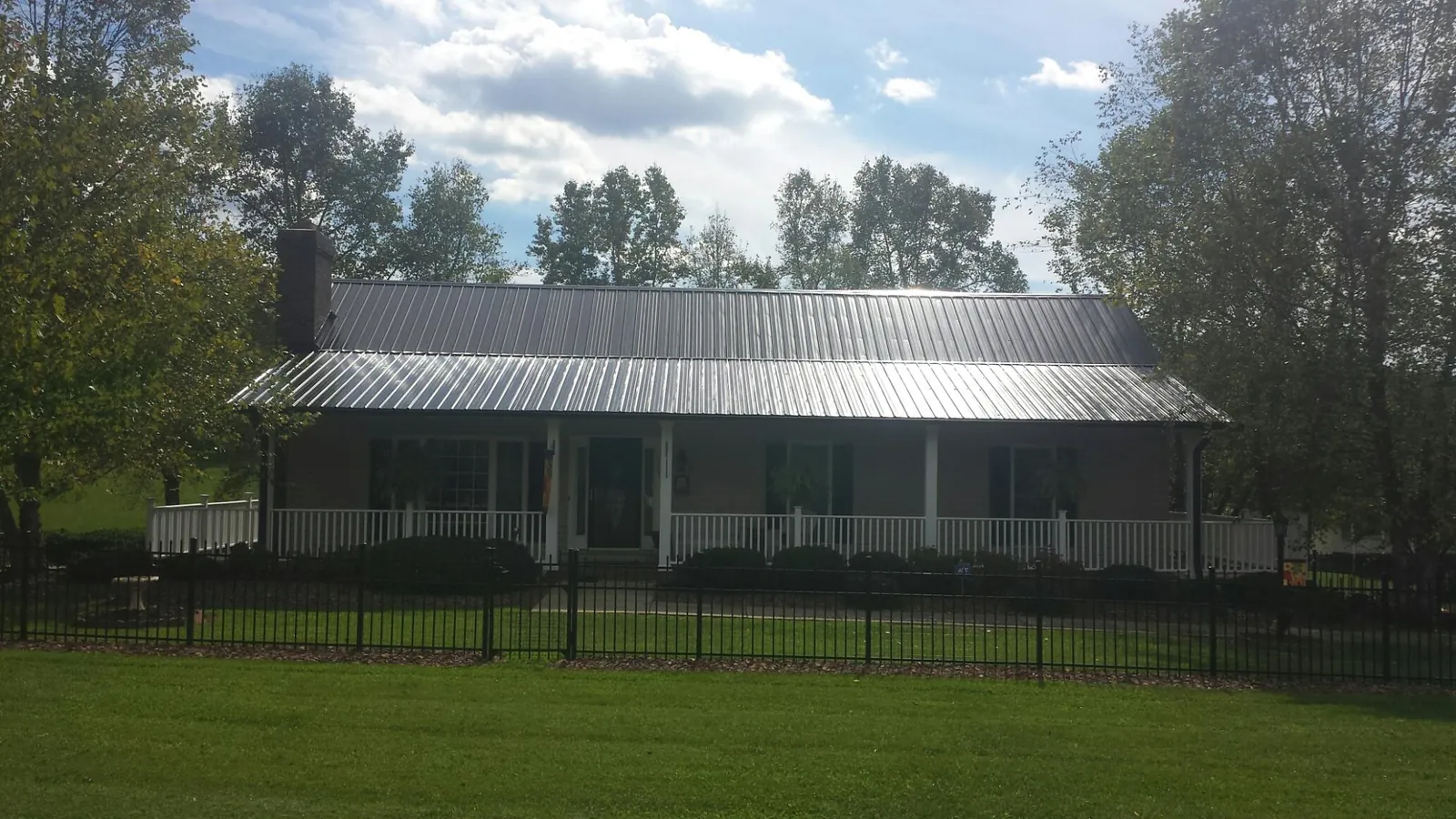 Gray metal roof on a brick ranch with a full width front porch — Gutter Guard Installation work by our crew in Richardsville