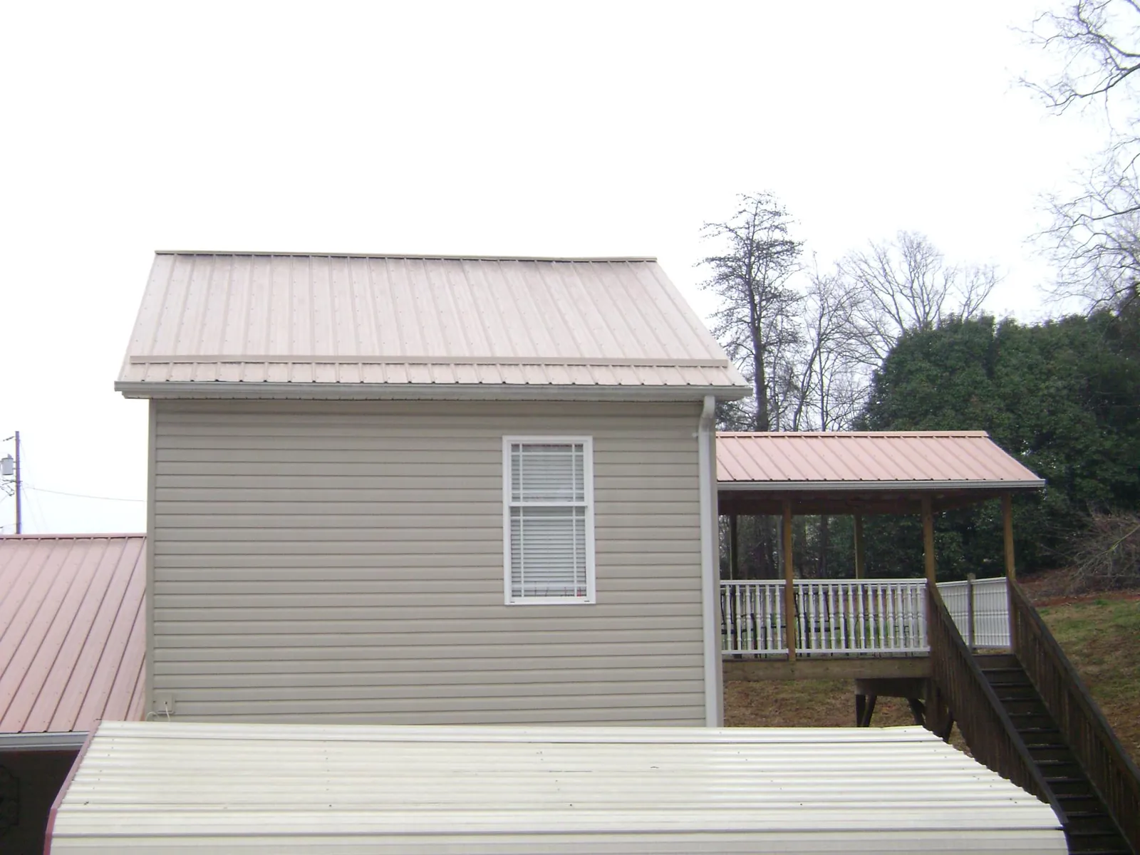 Tan metal roofs on a two story addition and attached porch, from a Roof Replacement job in Richardsville