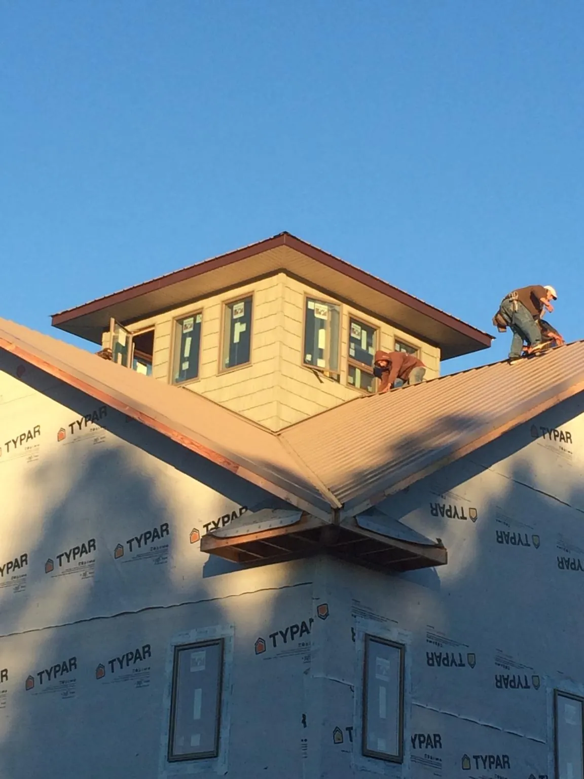 Roofers working around a rooftop cupola on a new metal roof at sunset — Roof Waterproofing in Richardsville by Roofing Brothers